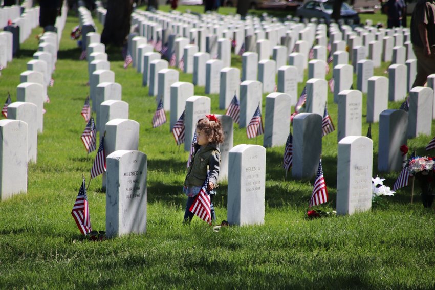 Vivienne Dauro, 1, wanders among the headstones at Fort Logan National Cemetery. Vivenne's dad Michael, a former Navy SEAL, brings his three daughters to the cemetery every year for Memorial Day.